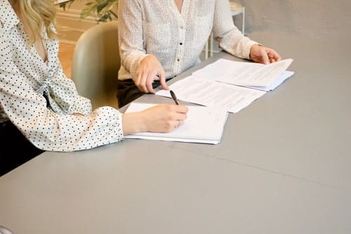 duas mulheres conferindo documentos e assinando um deles